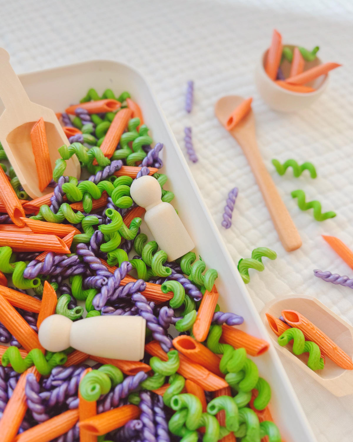 Whack-a-Noodles pasta with wooden peg doll, scoop and bowl on a white tray