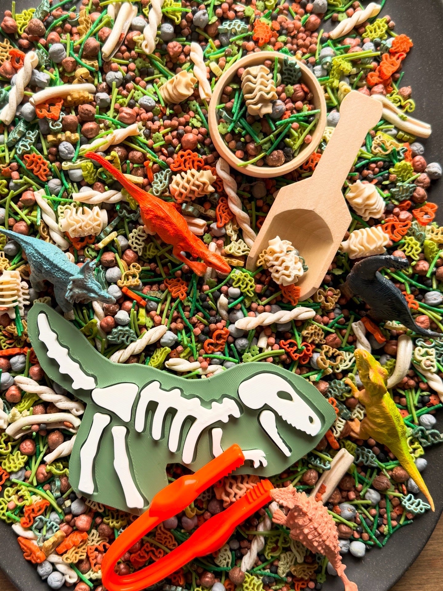 Overhead Dino Dig play kit with T-rex fossil dig piece, dinosaurs, tweezers and scoops in earthy filler