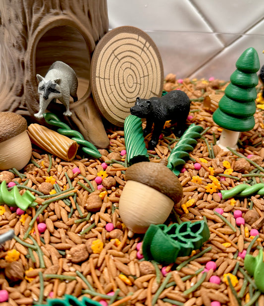 Woodland sensory bin with raccoon, black bear, acorns, log den and green pine tree
