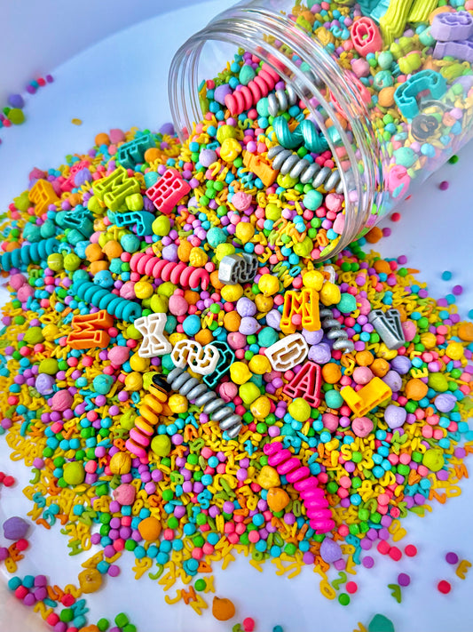 Jar of Kool School pastel sensory filler spilling letter beads and colorful pasta