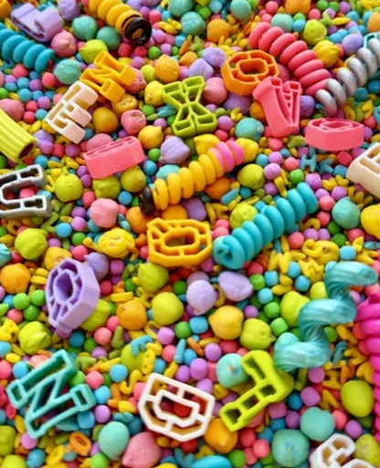 Close-up of Kool School sensory mix with pastel letter beads, pencil pasta and colorful beads