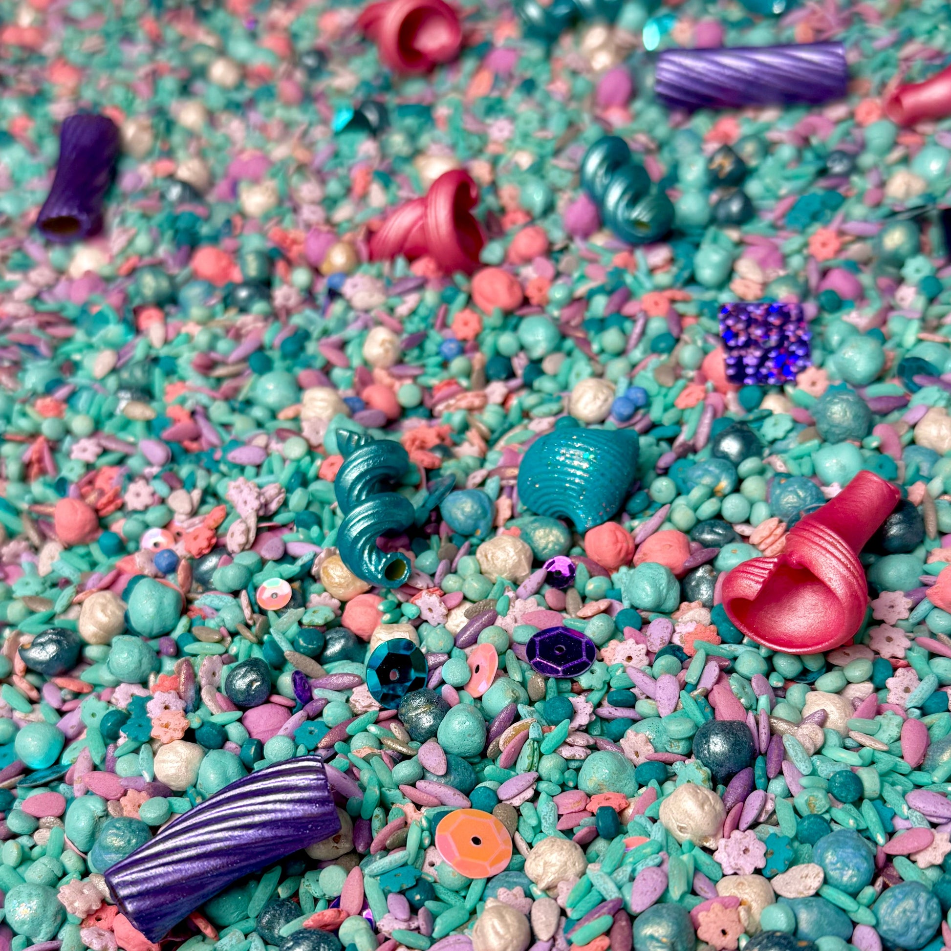 Mermaid Magic sensory filler with metallic teal shells, pink accents and purple spirals