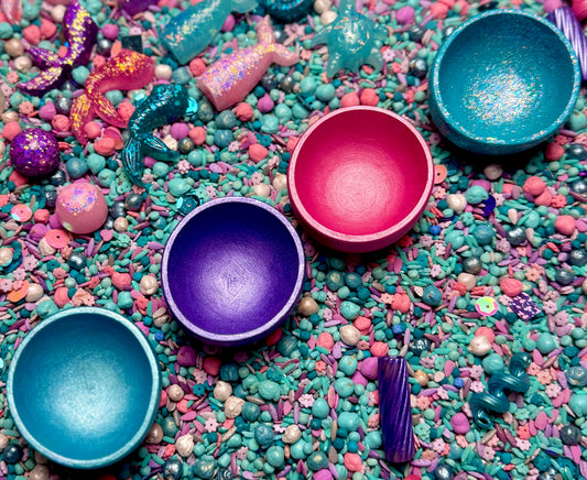 Shimmery sorting bowls in teal, pink, purple and blue nestled in mermaid sensory filler